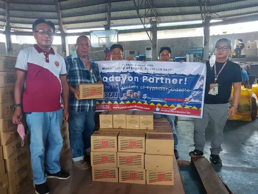 Group of men holding boxes and a banner, appearing to be a donation.