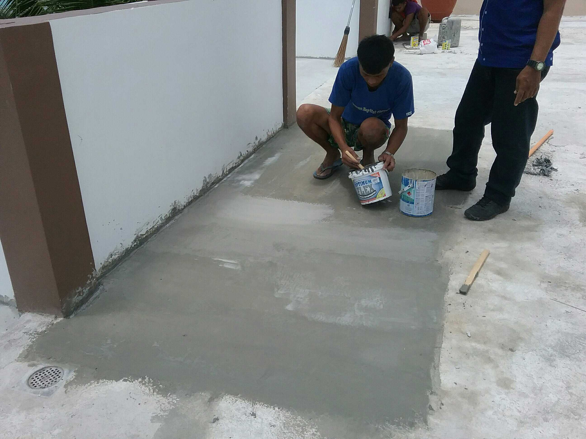 Roofers installing dark gray shingles on a roof under a bright blue sky.