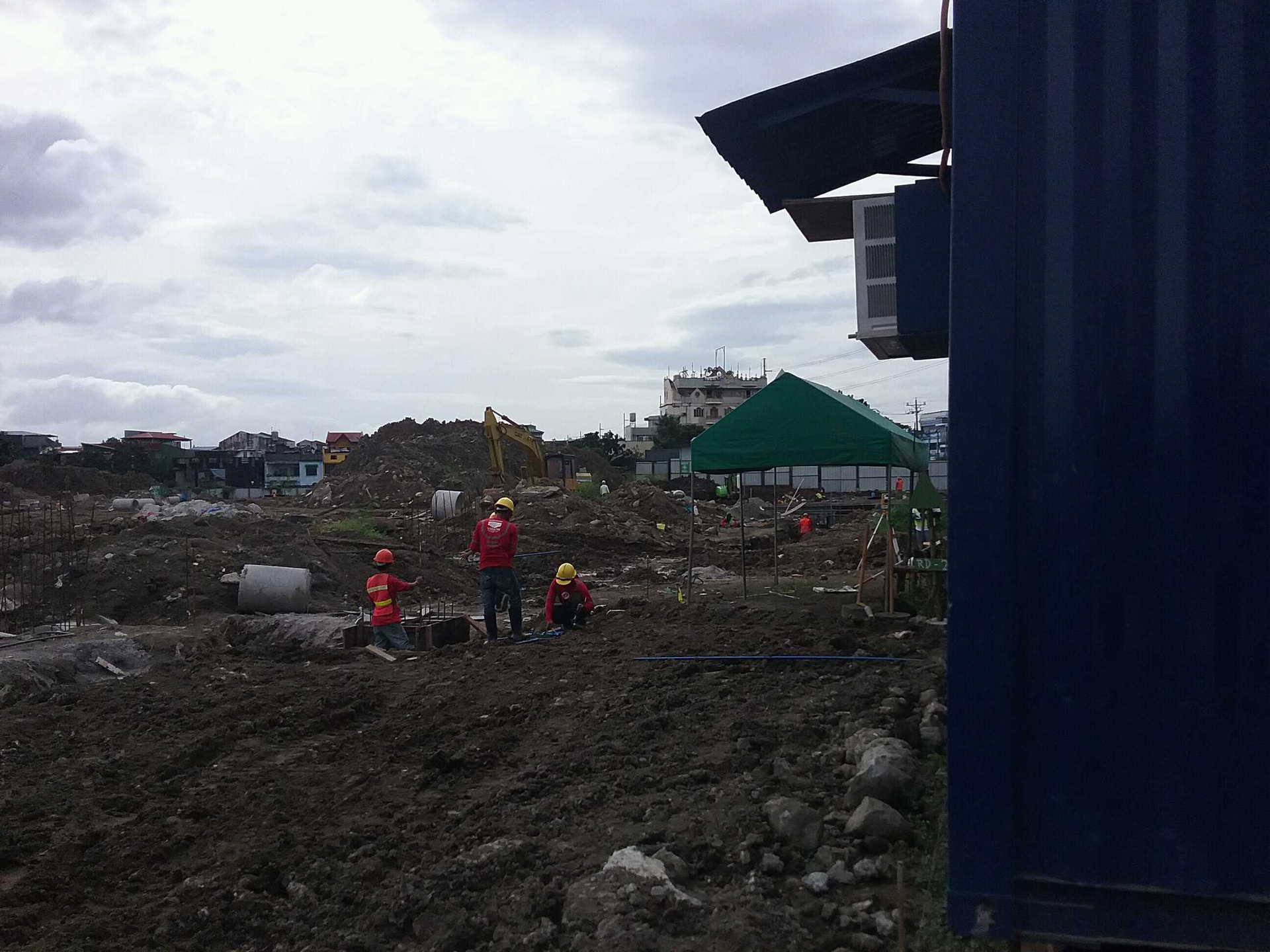 Construction of a multi-story house; workers with a yellow telescopic handler. Green sheathing on wood frames.