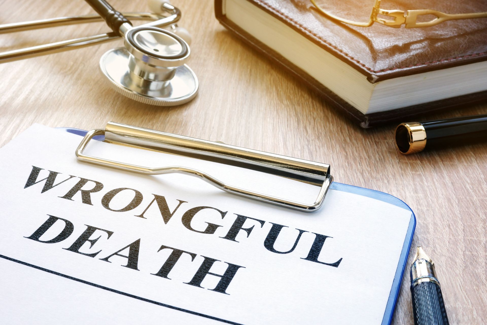 Clipboard with “WRONGFUL DEATH” beside a stethoscope and legal books on a desk Clipboard with “WRONGFUL DEATH” beside a stethoscope and legal books on a desk