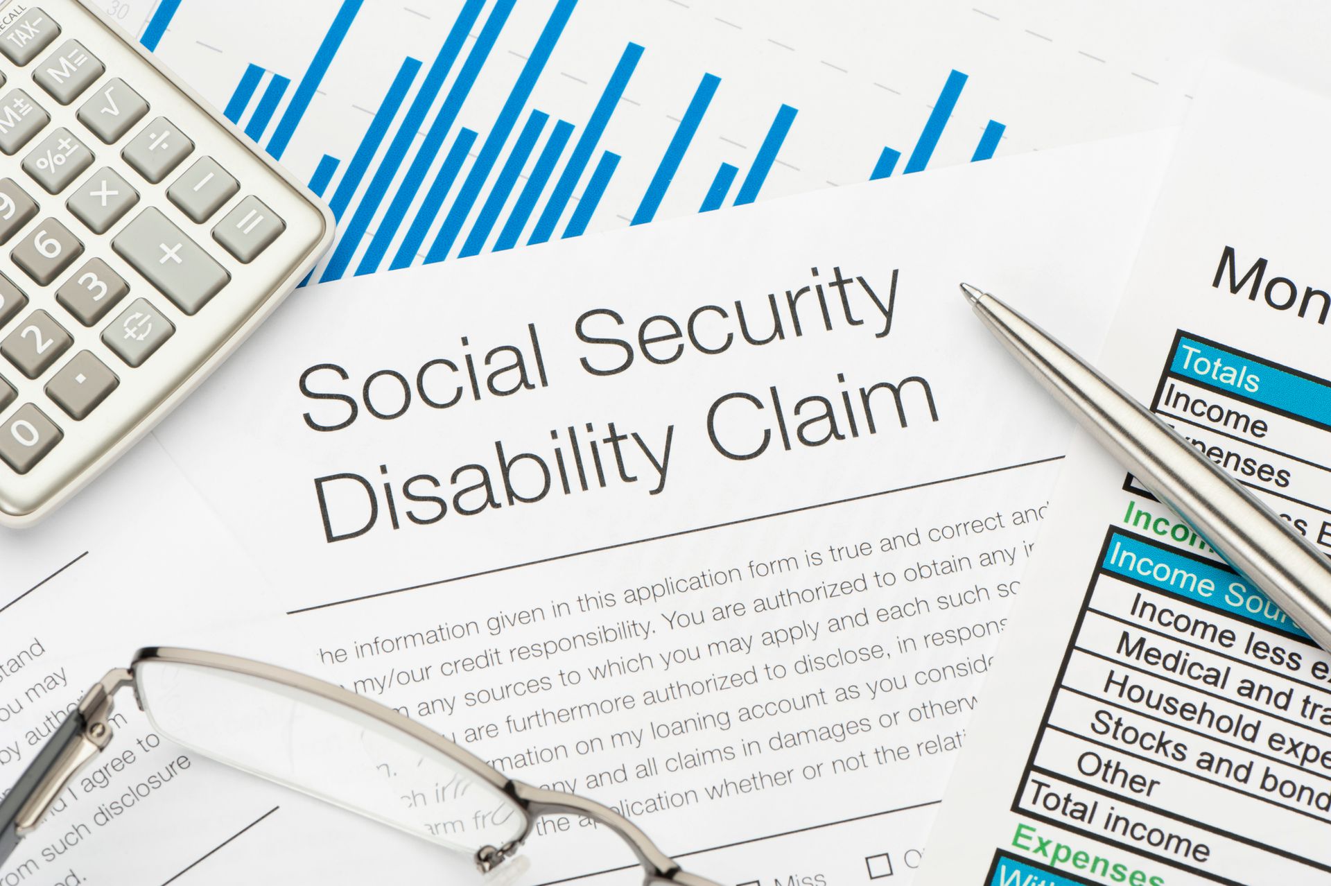 A social security disability claim form with a pen and calculator — Willmar, MN — Schneider & Madsen PC