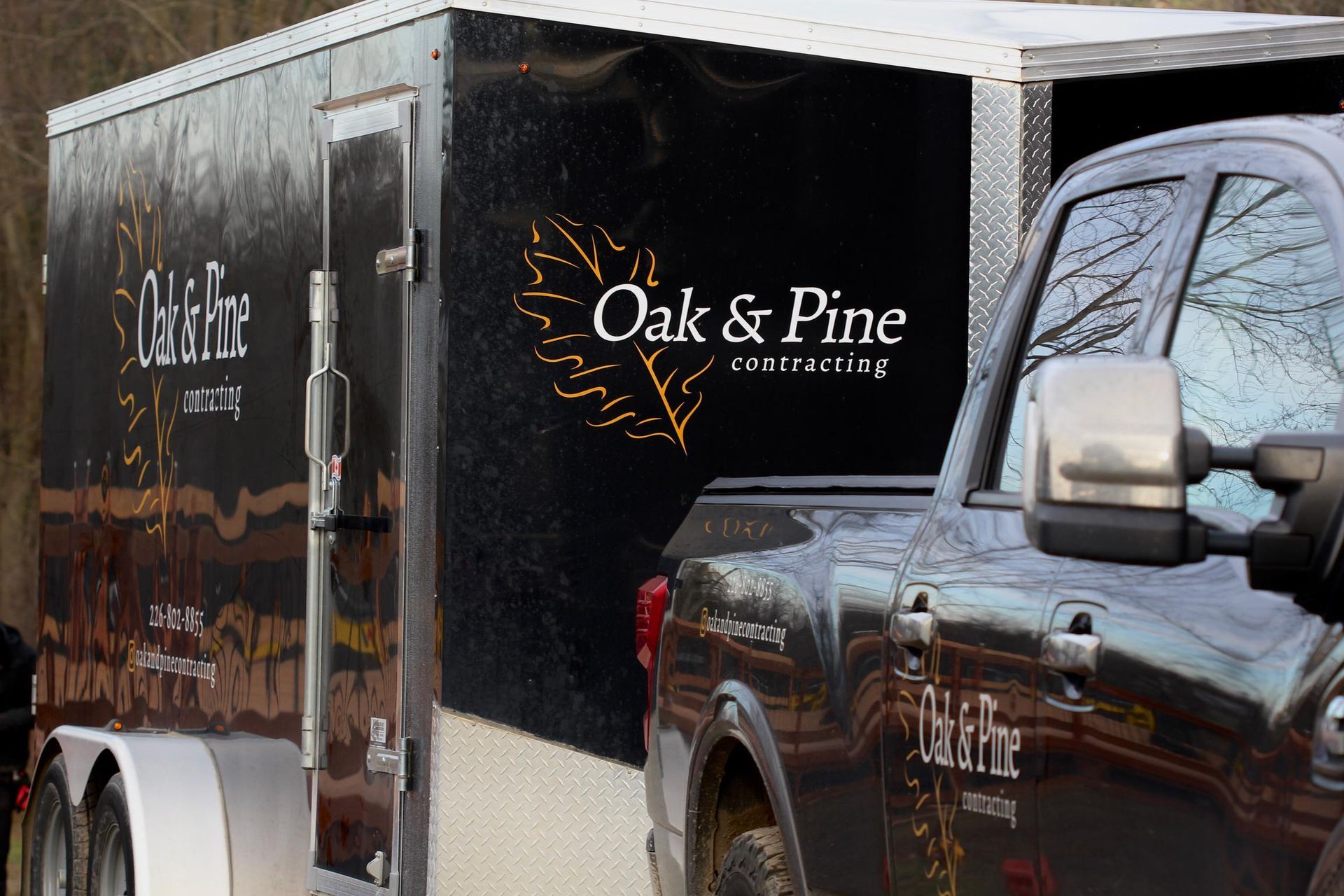 A truck is parked next to a trailer that says oak & pine on it.