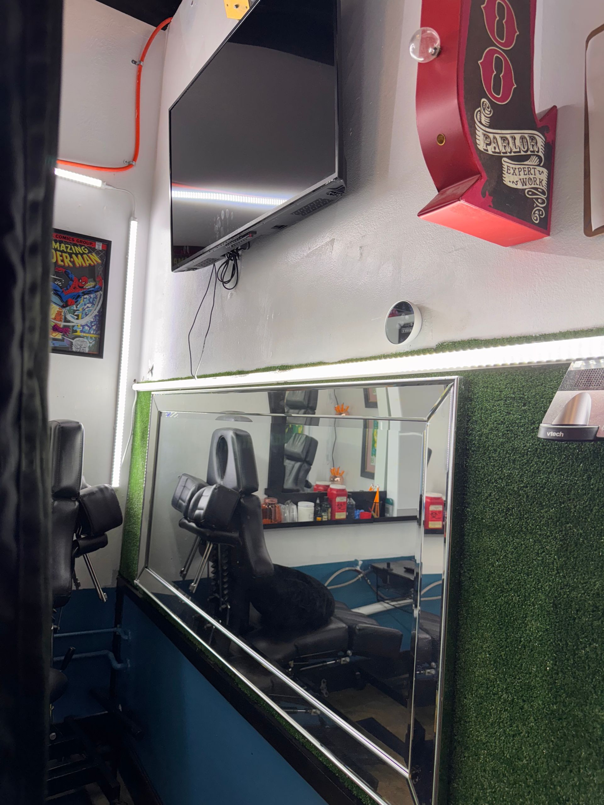 A barber shop with a large mirror and a flat screen tv on the wall.