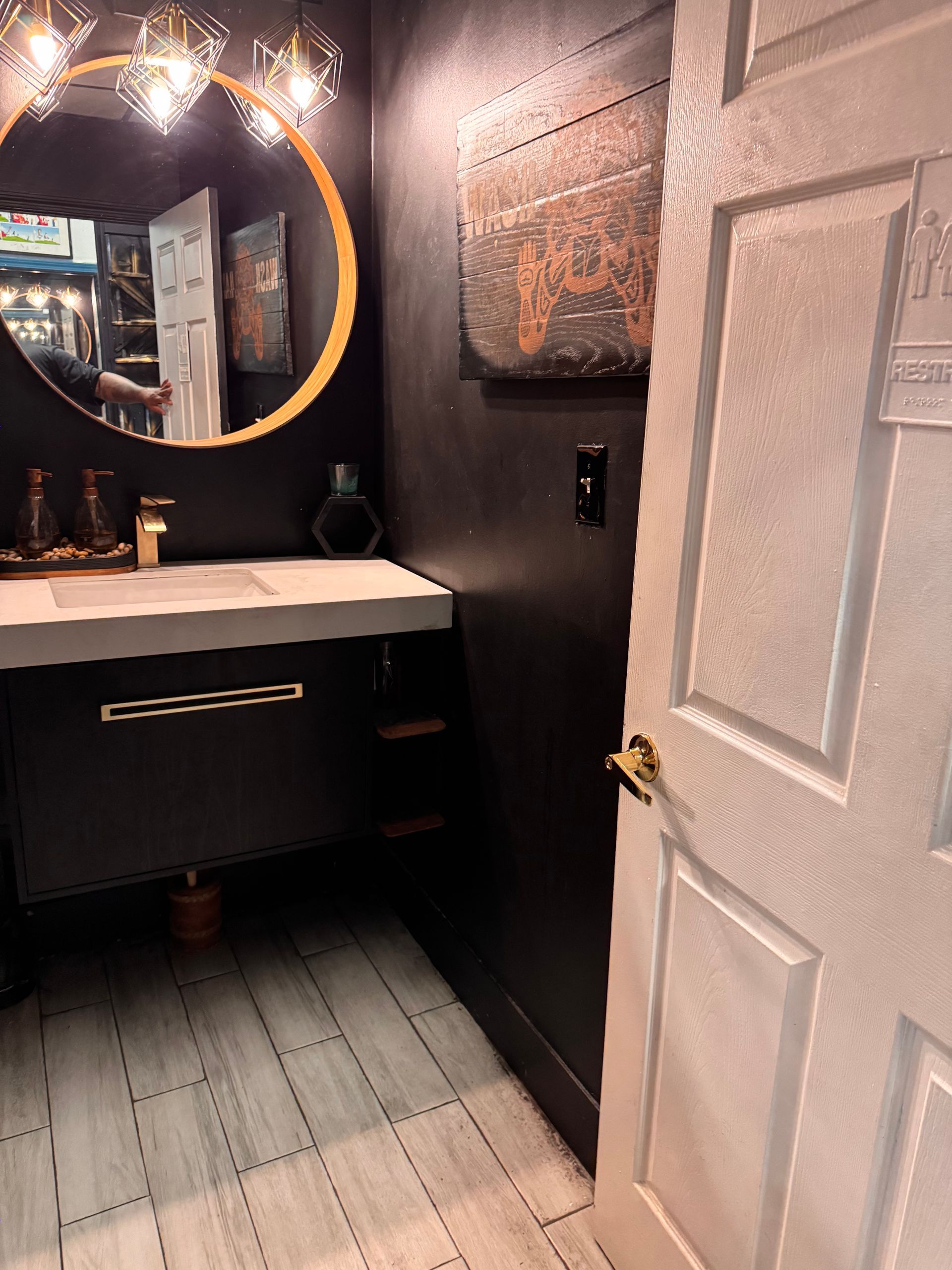 A bathroom with a sink , mirror and a door.