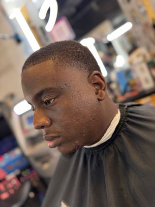 A man is getting his hair cut at a barber shop.
