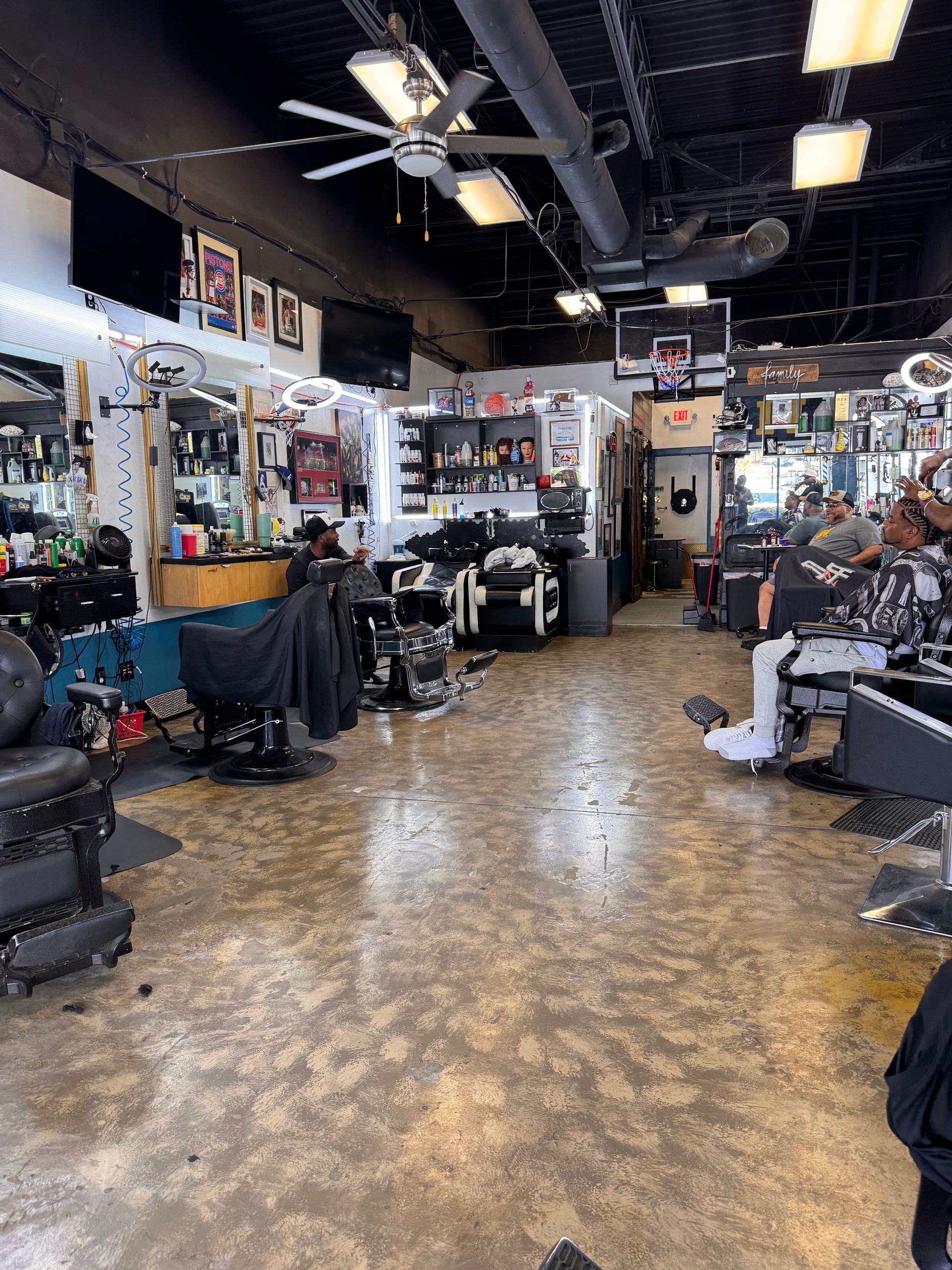 A barber shop with a lot of chairs and a ceiling fan.