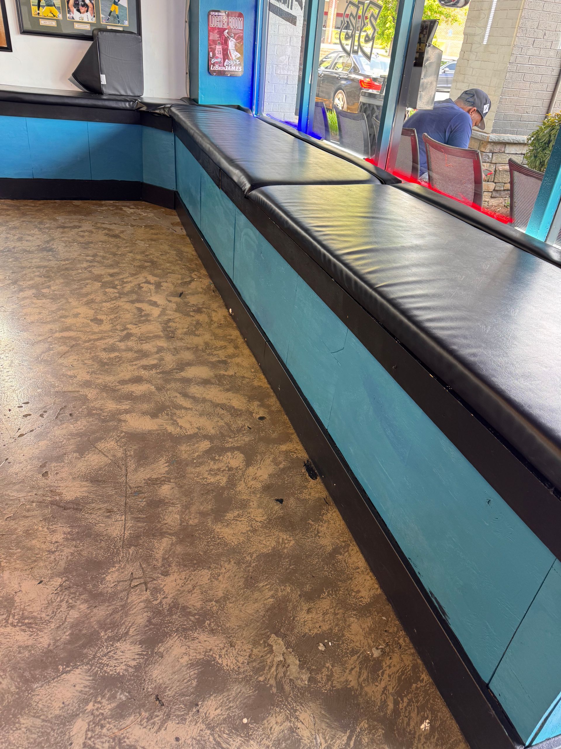 A man is sitting at a table in front of a window in a restaurant.