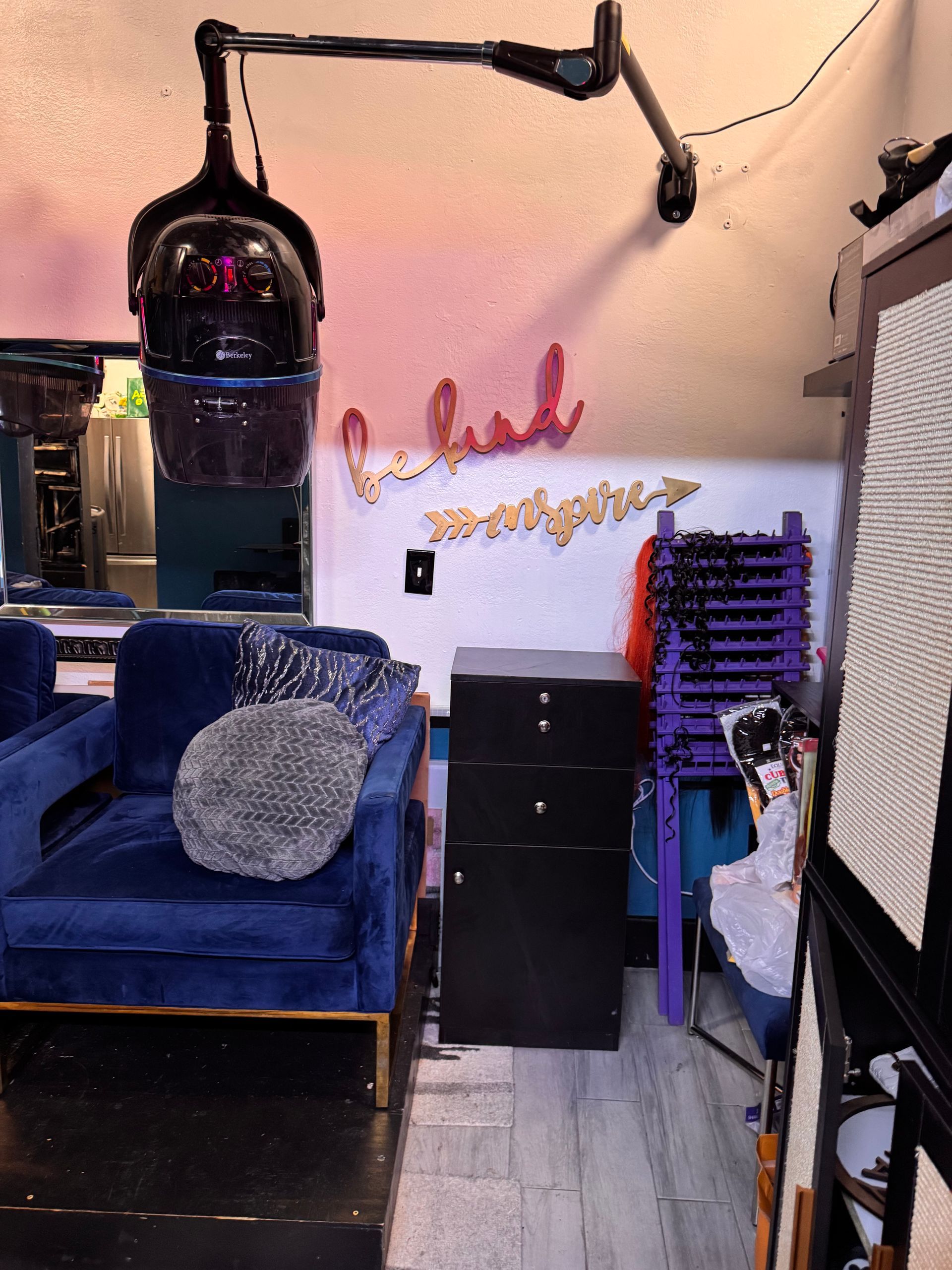 A room with a blue chair and a hair dryer on the wall