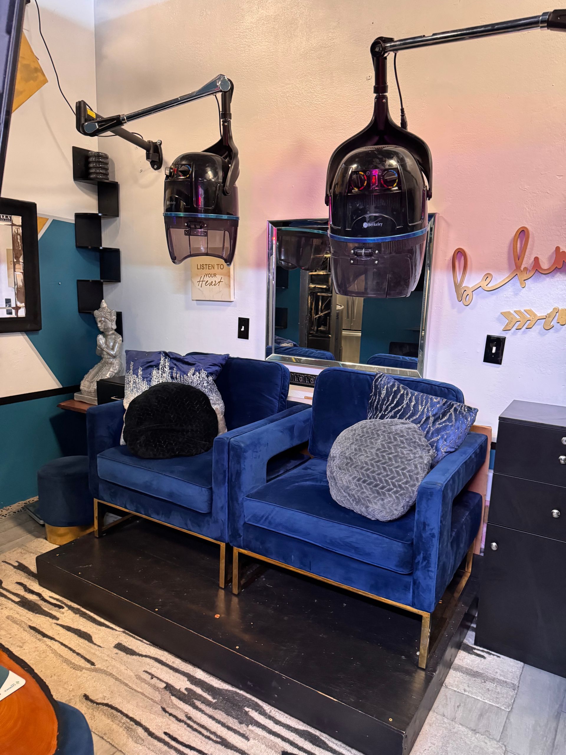 A room with two blue chairs and two hair dryers hanging from the ceiling.
