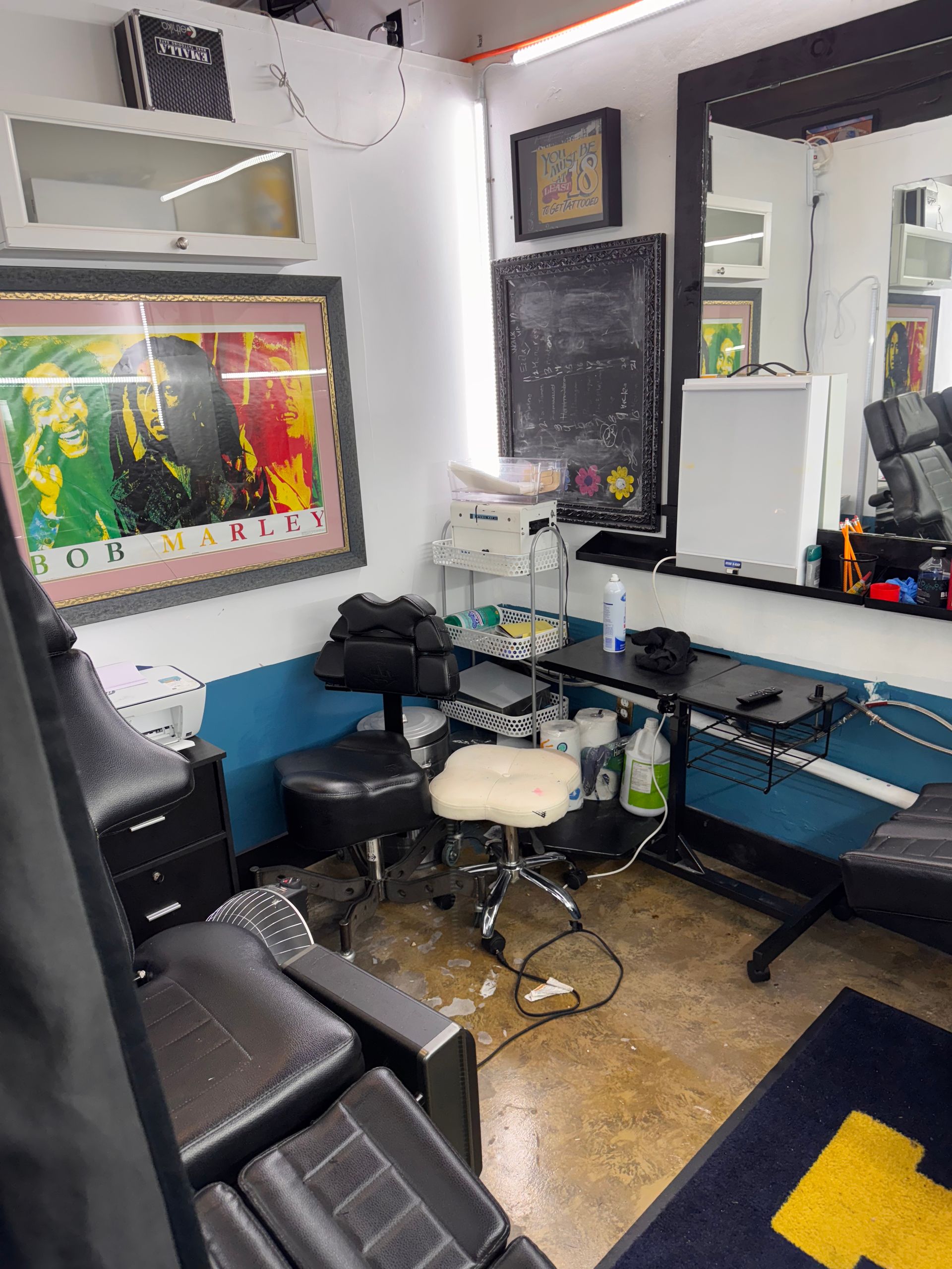 A room with a chair , desk , mirror and a picture on the wall.