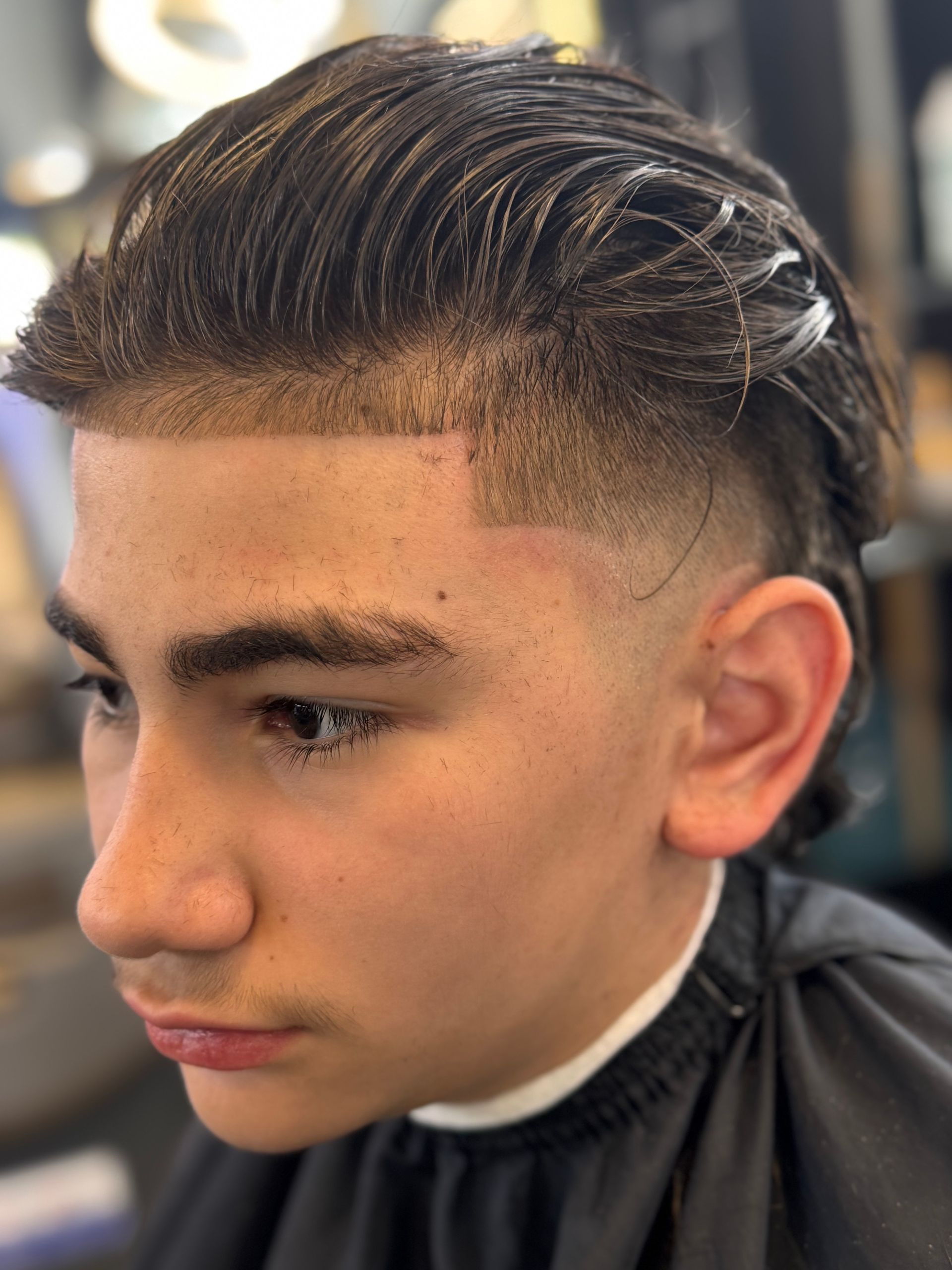 A young boy is getting his hair cut at a barber shop