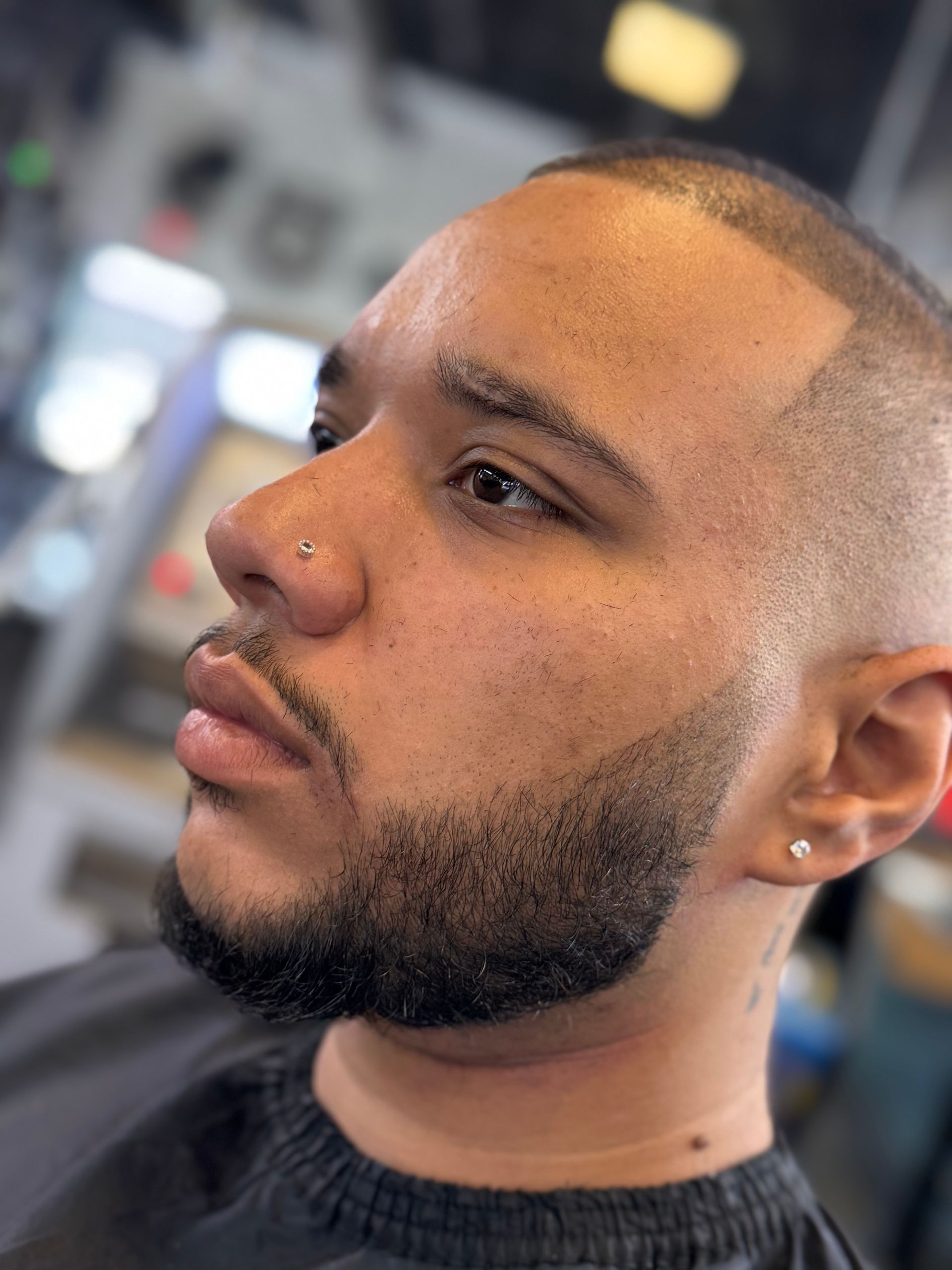 A man with a beard is getting his hair cut at a barber shop.