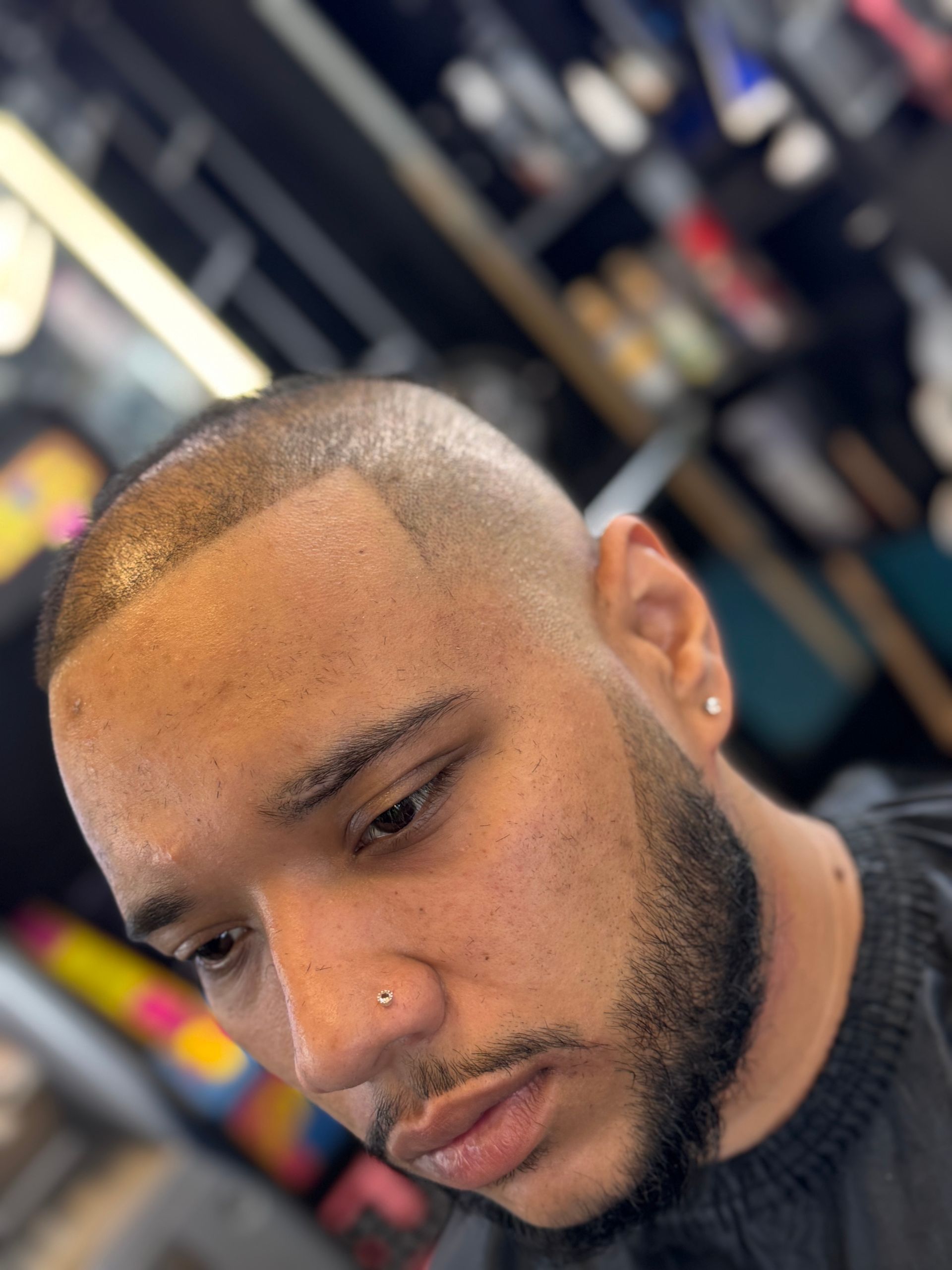 A man with a beard is getting his hair cut at a barber shop.