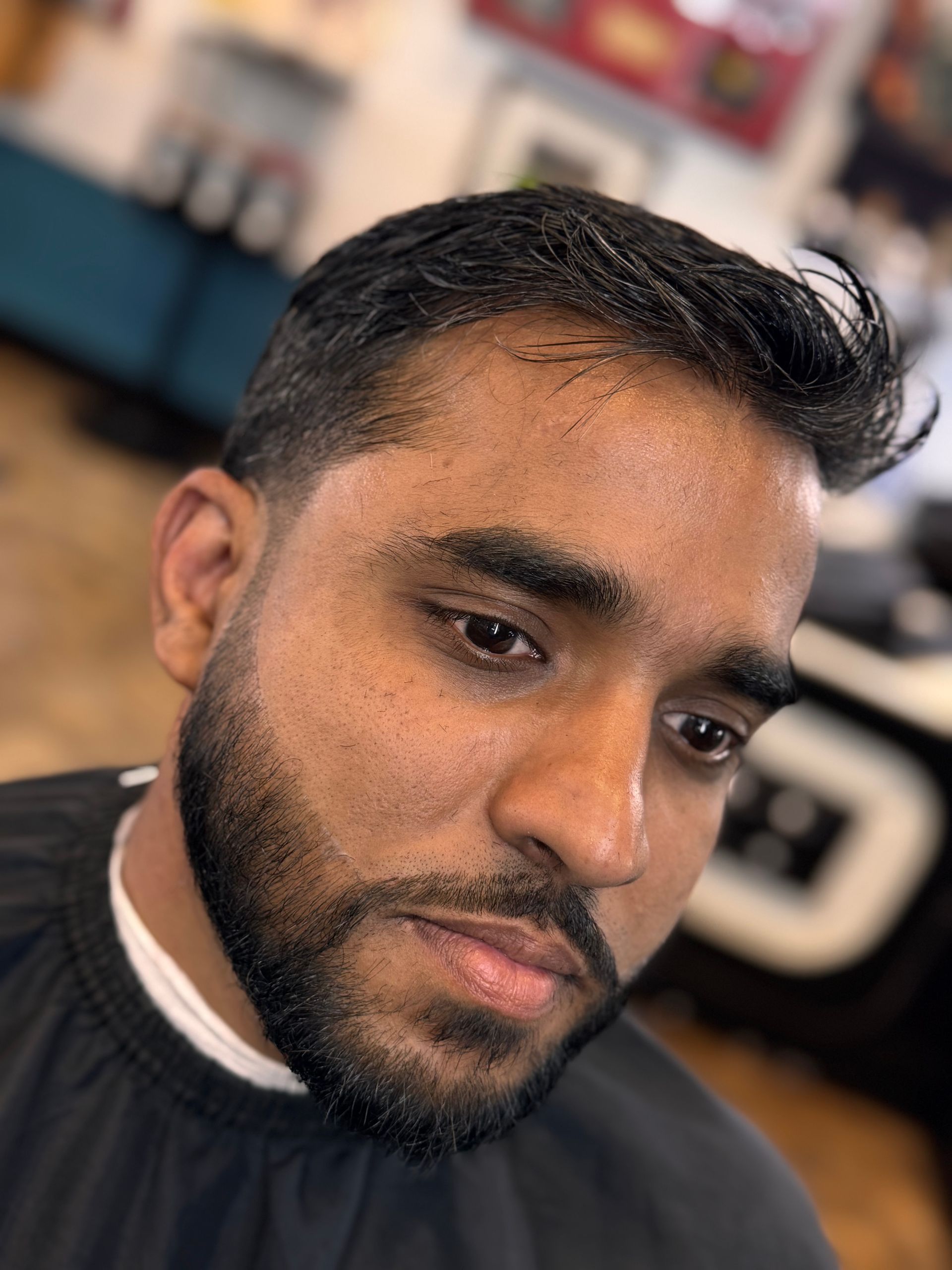 A man with a beard is getting his hair cut at a barber shop.