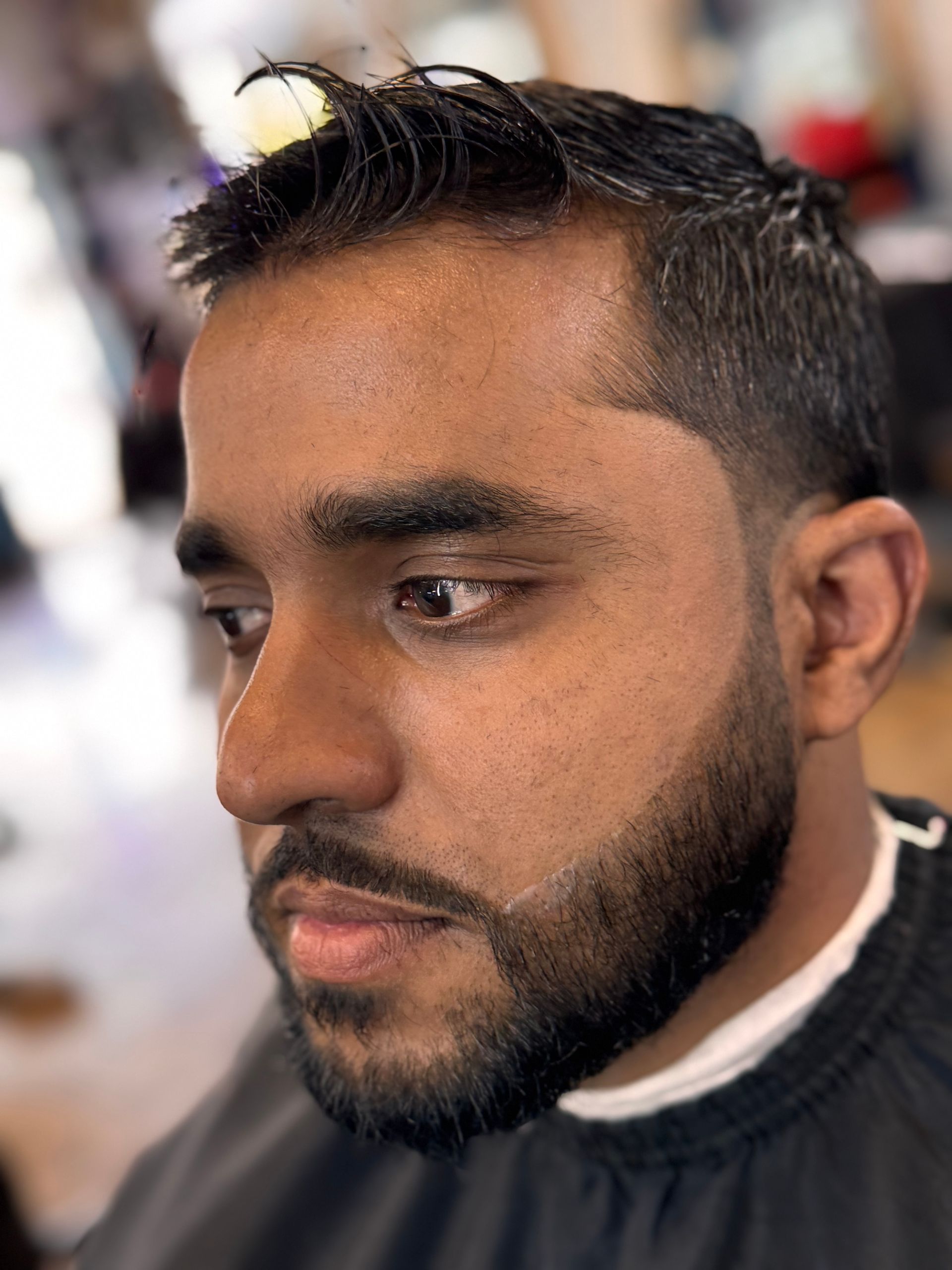 A man with a beard is getting his hair cut at a barber shop.