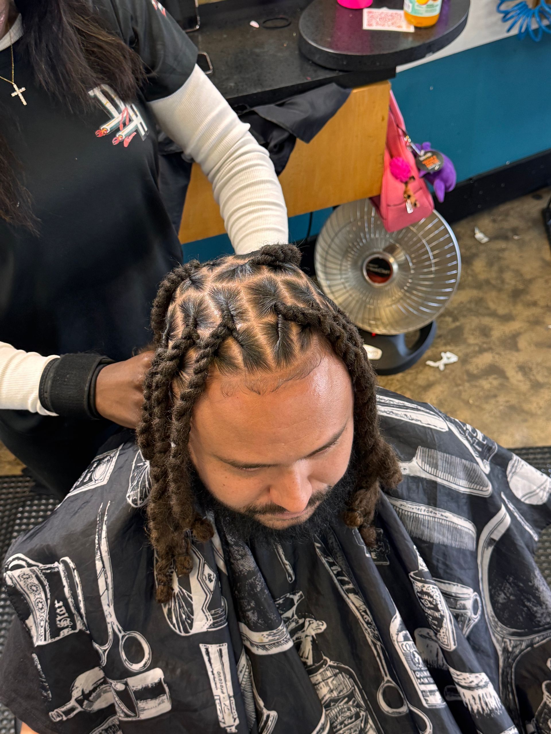A man is getting his hair braided at a barber shop