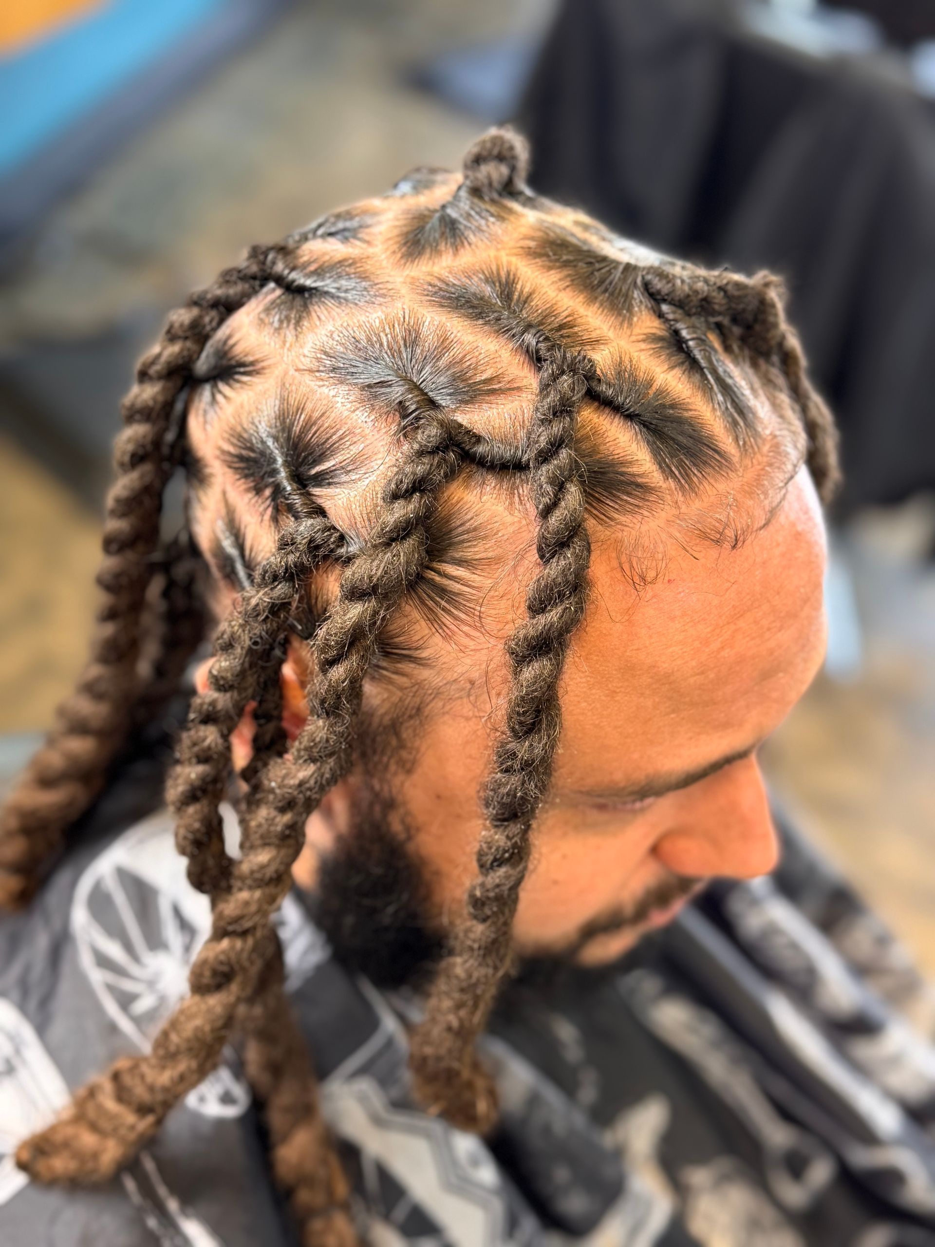 A man with dreadlocks and a beard is sitting at a barber shop.