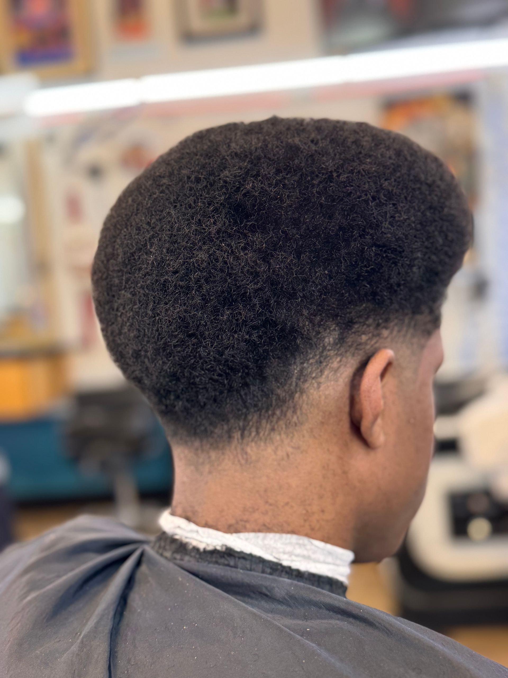 A man is getting his hair cut at a barber shop.