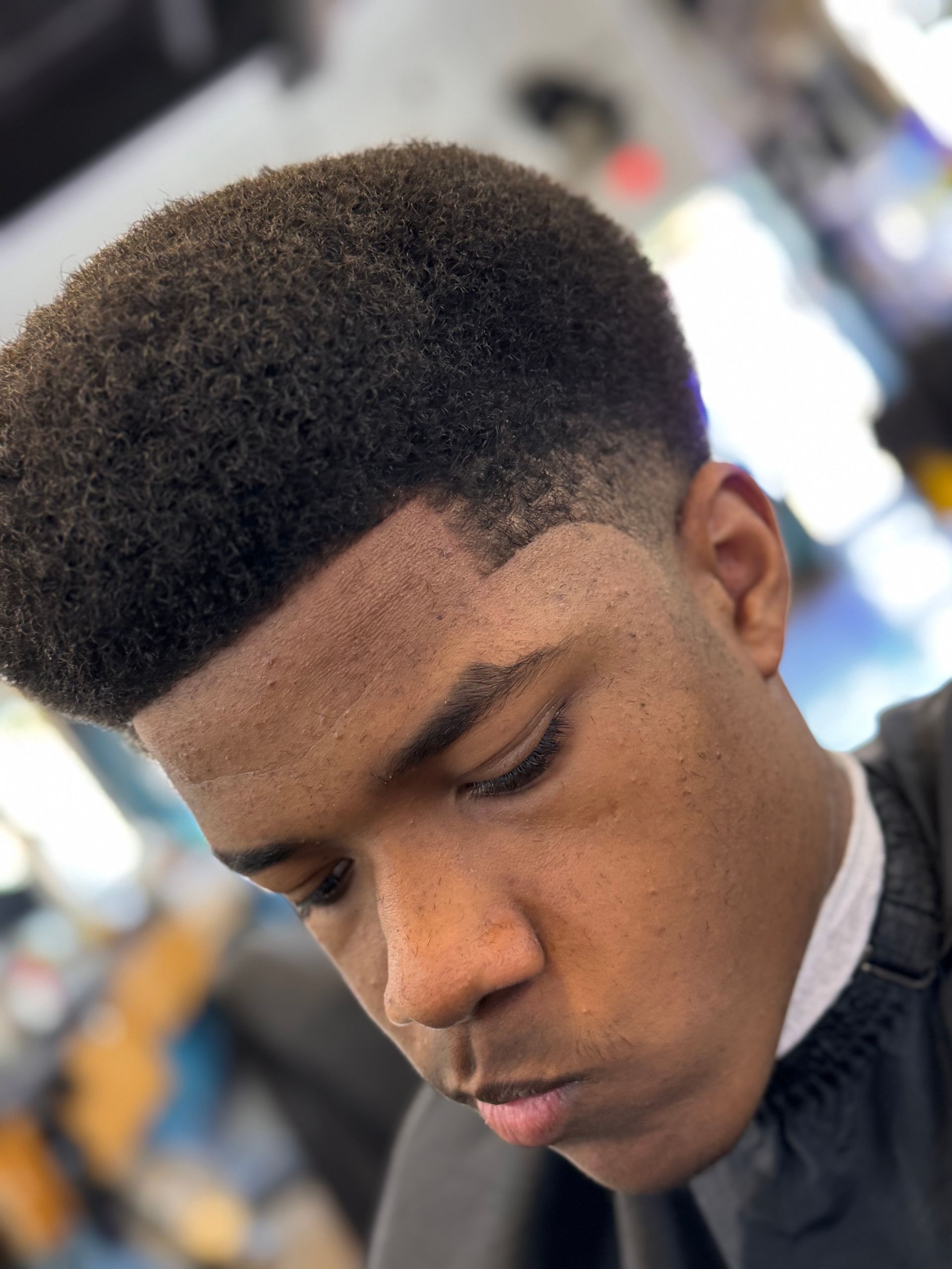 A young man is getting his hair cut at a barber shop.