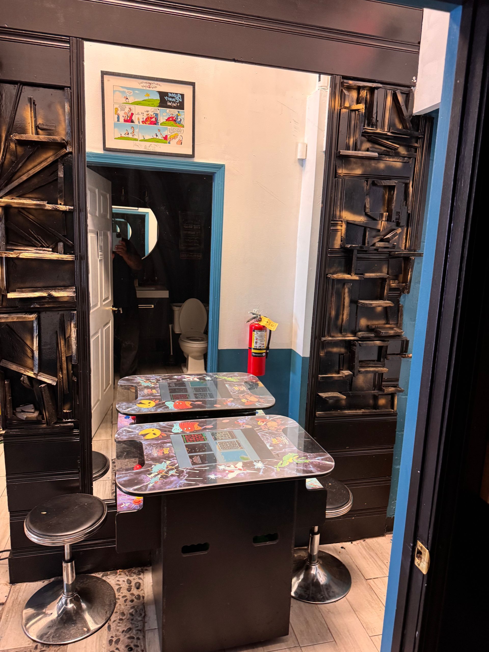 A room with two arcade tables and a fire extinguisher.