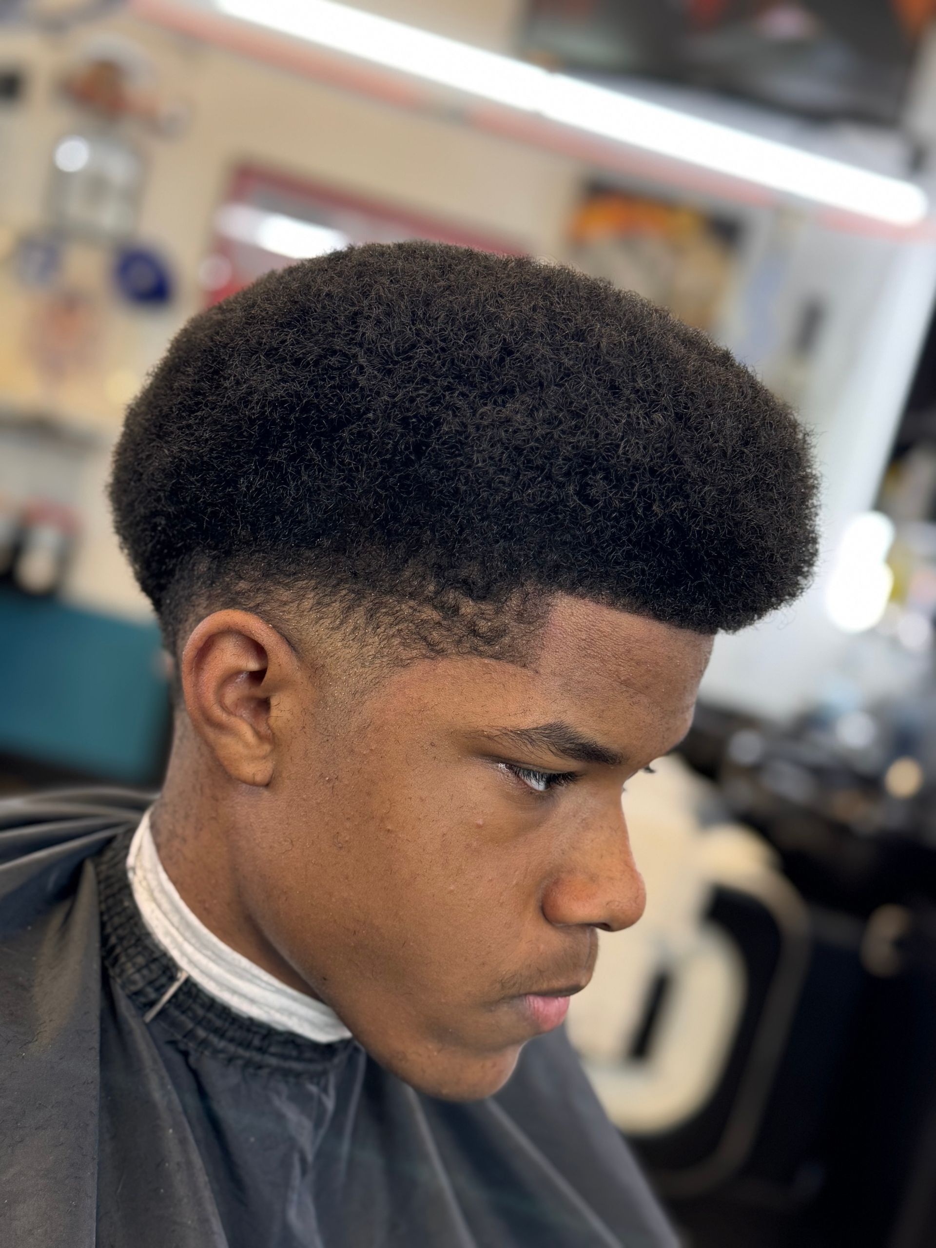 A young man is getting his hair cut at a barber shop.