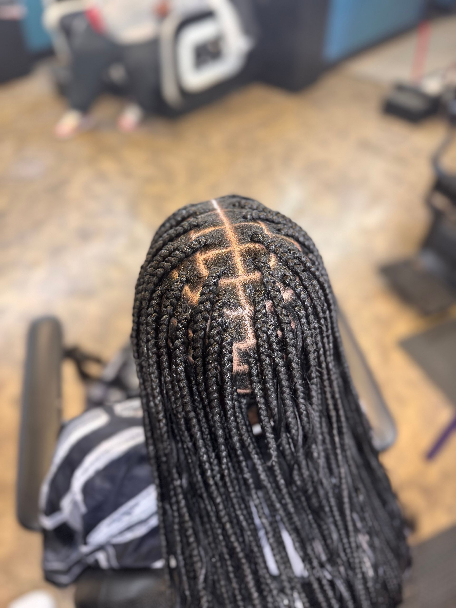 A woman with braids in her hair is sitting in a chair.