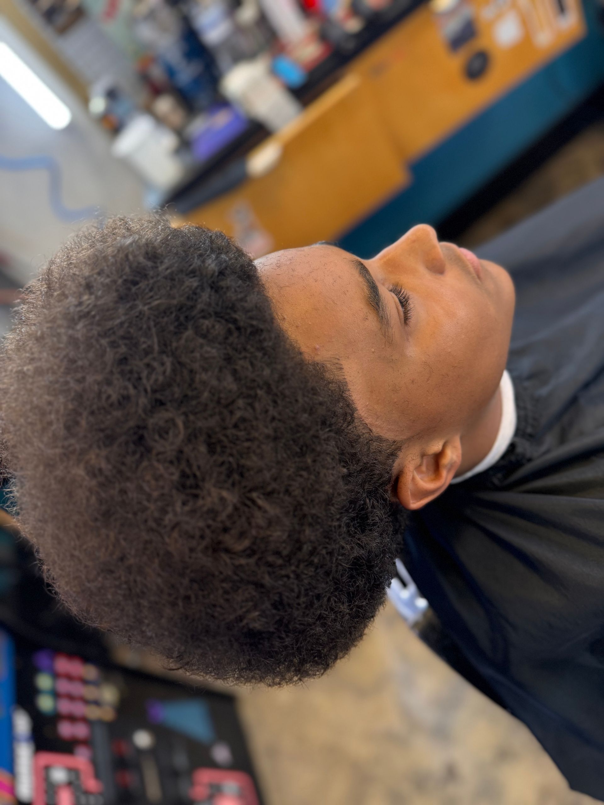 A young boy is getting his hair cut at a barber shop.