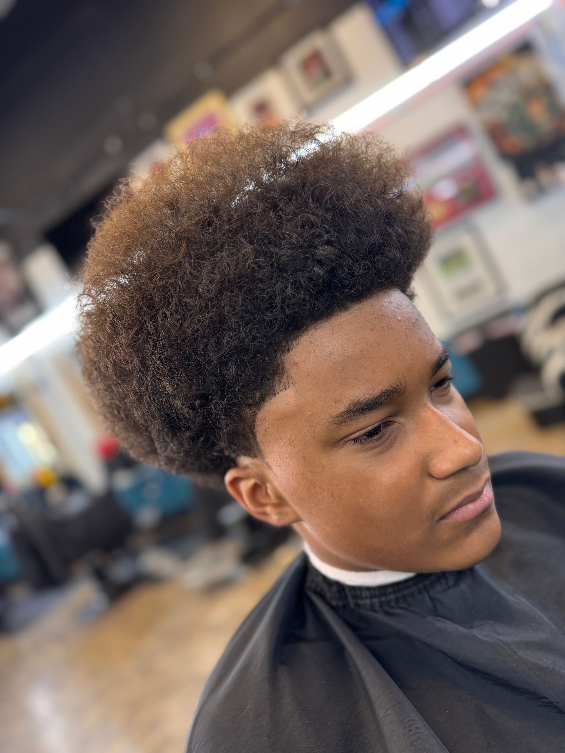 A young man is getting his hair cut at a barber shop.