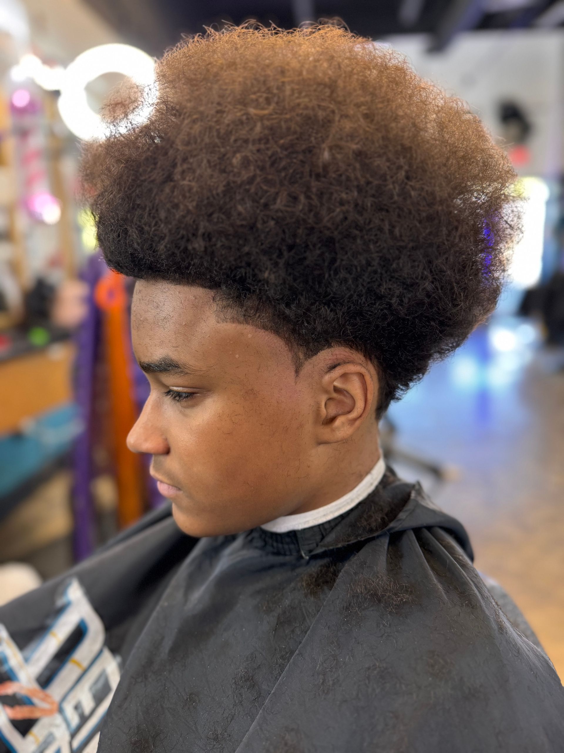 A young boy is getting his hair cut at a barber shop.