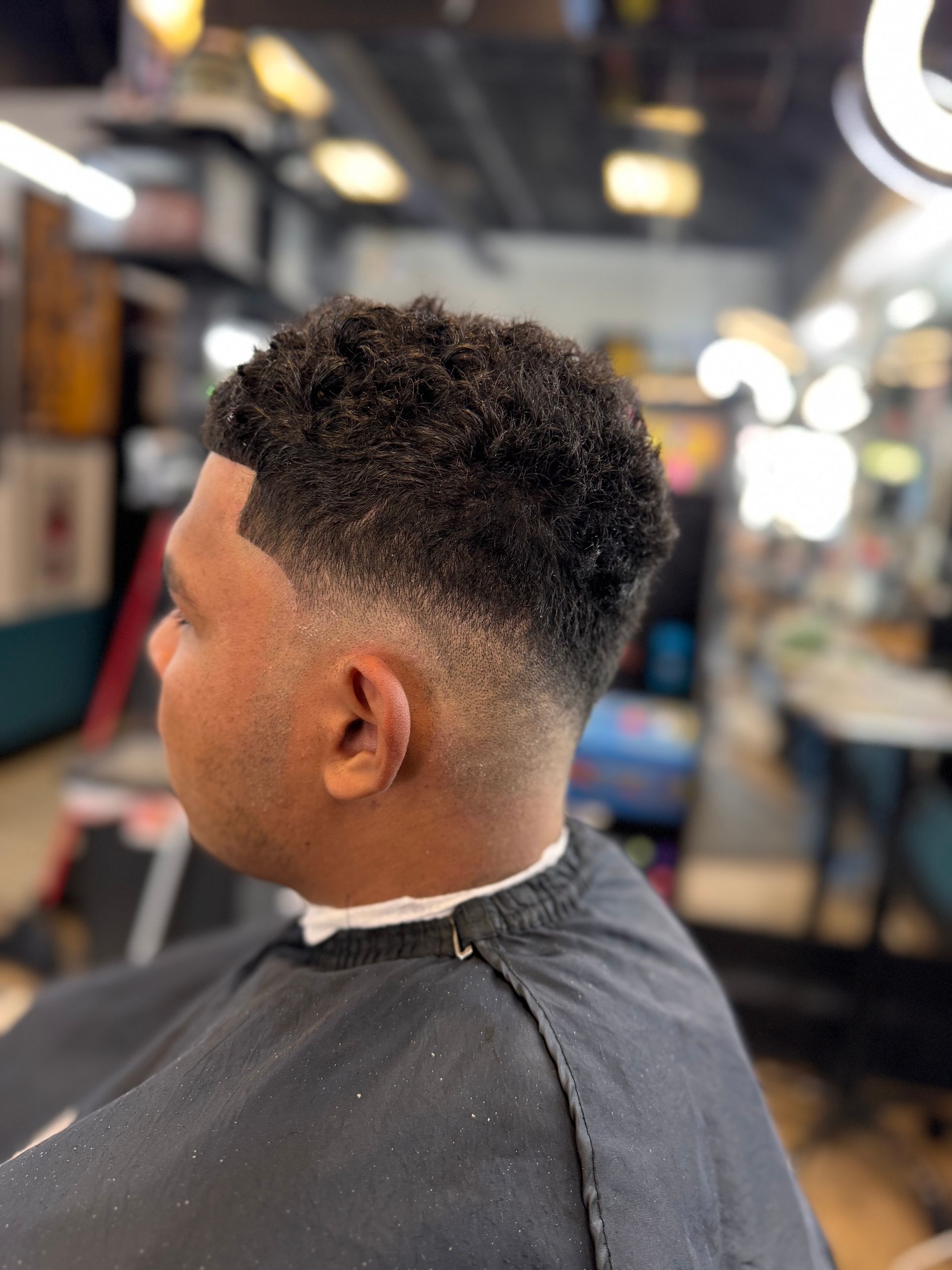 A man is getting his hair cut at a barber shop.