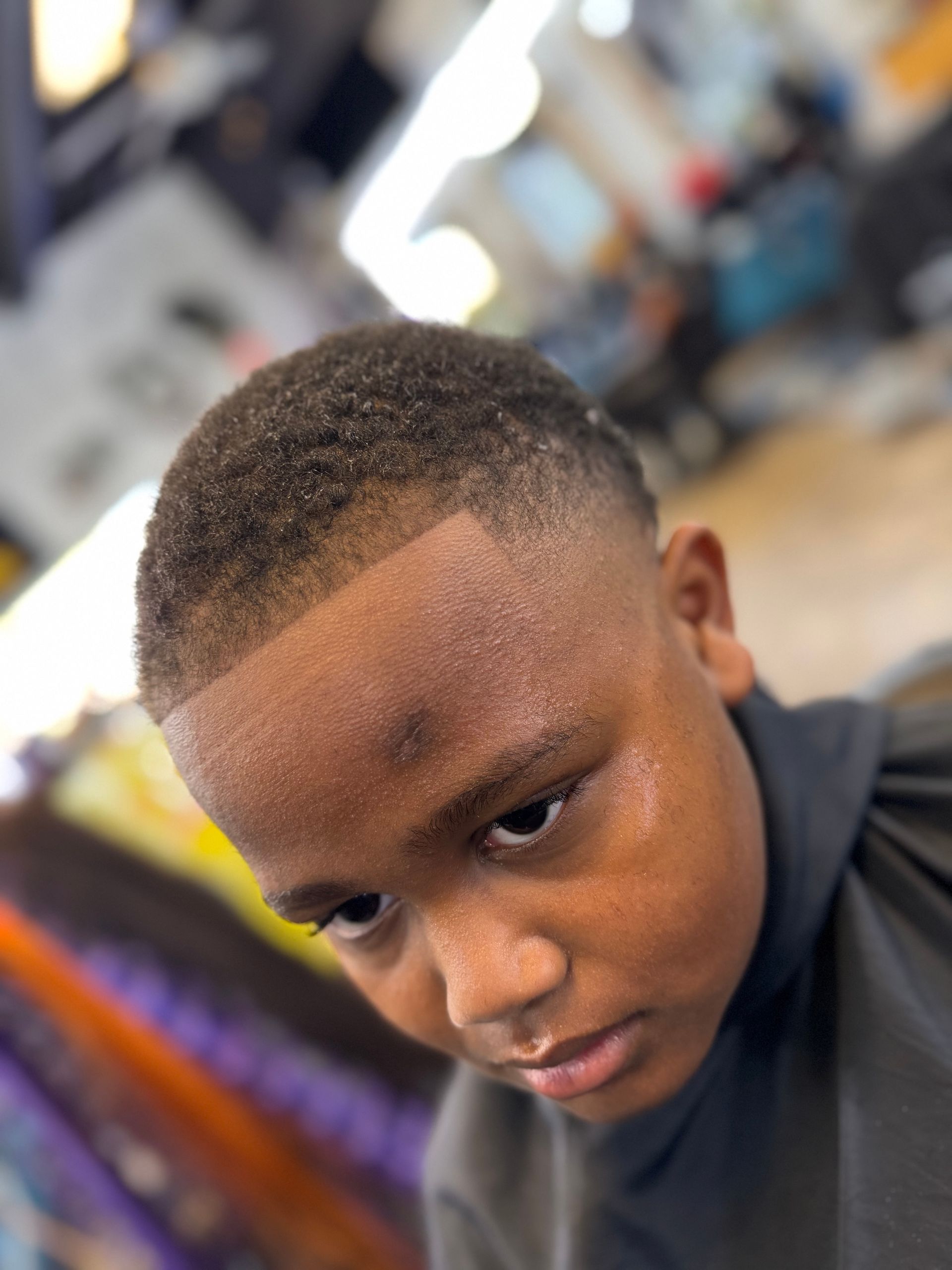 A young boy is getting his hair cut at a barber shop.