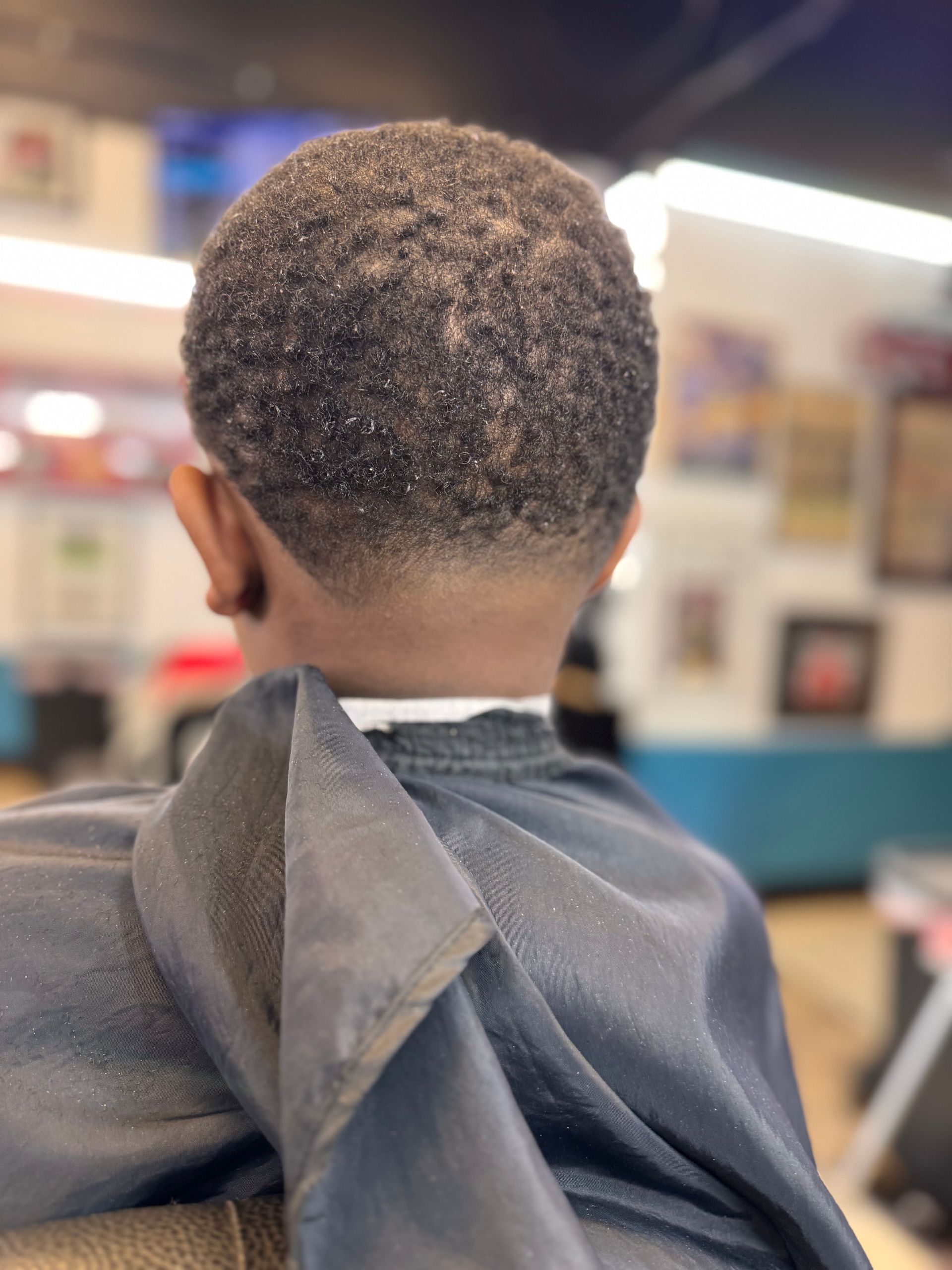 A young boy is getting his hair cut at a barber shop.