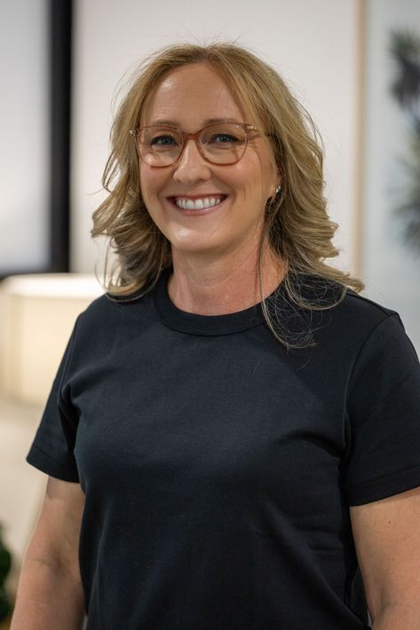 A woman wearing glasses and a black shirt is smiling for the camera.