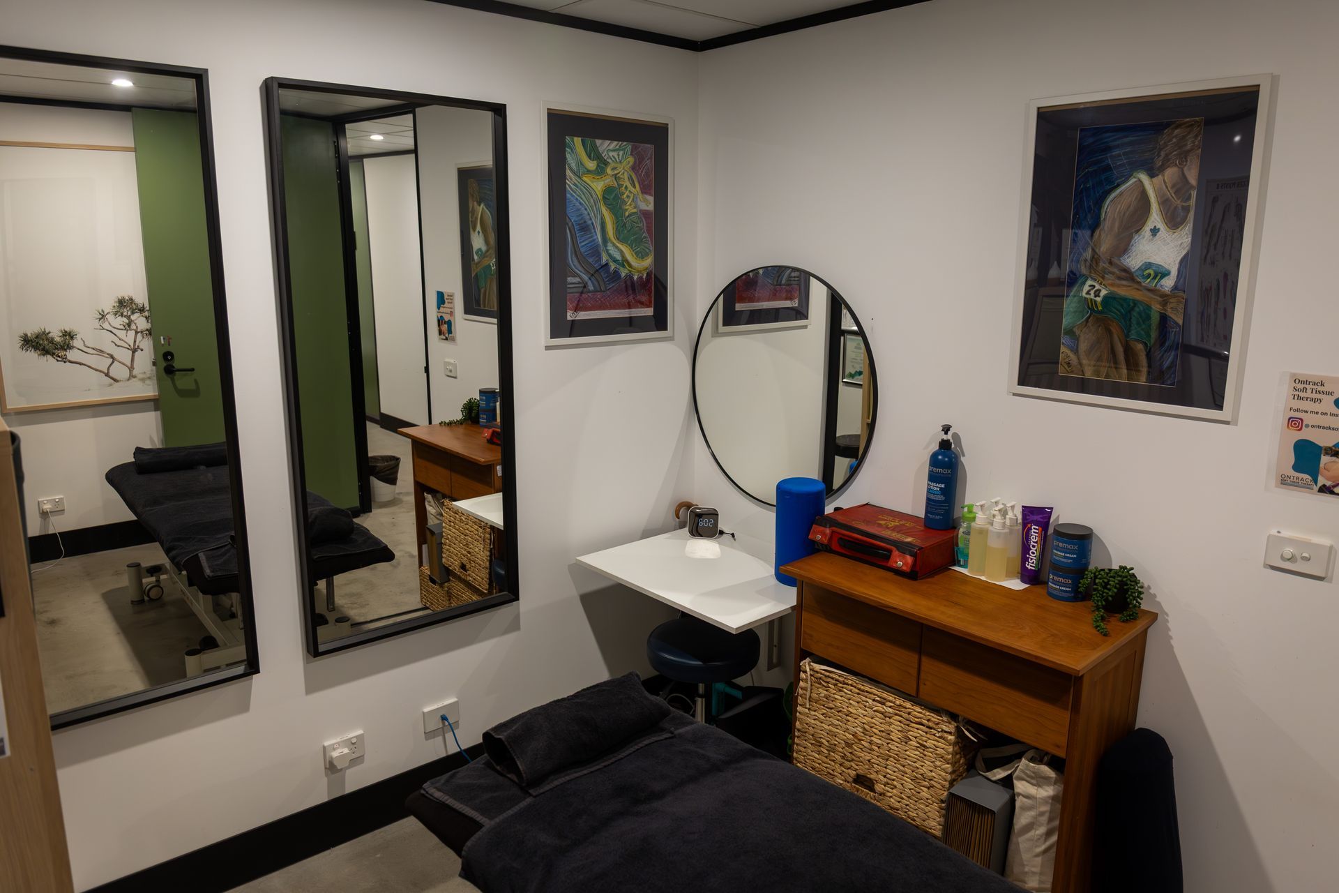 Small room with treatment table, mirrors, desk, and posters.