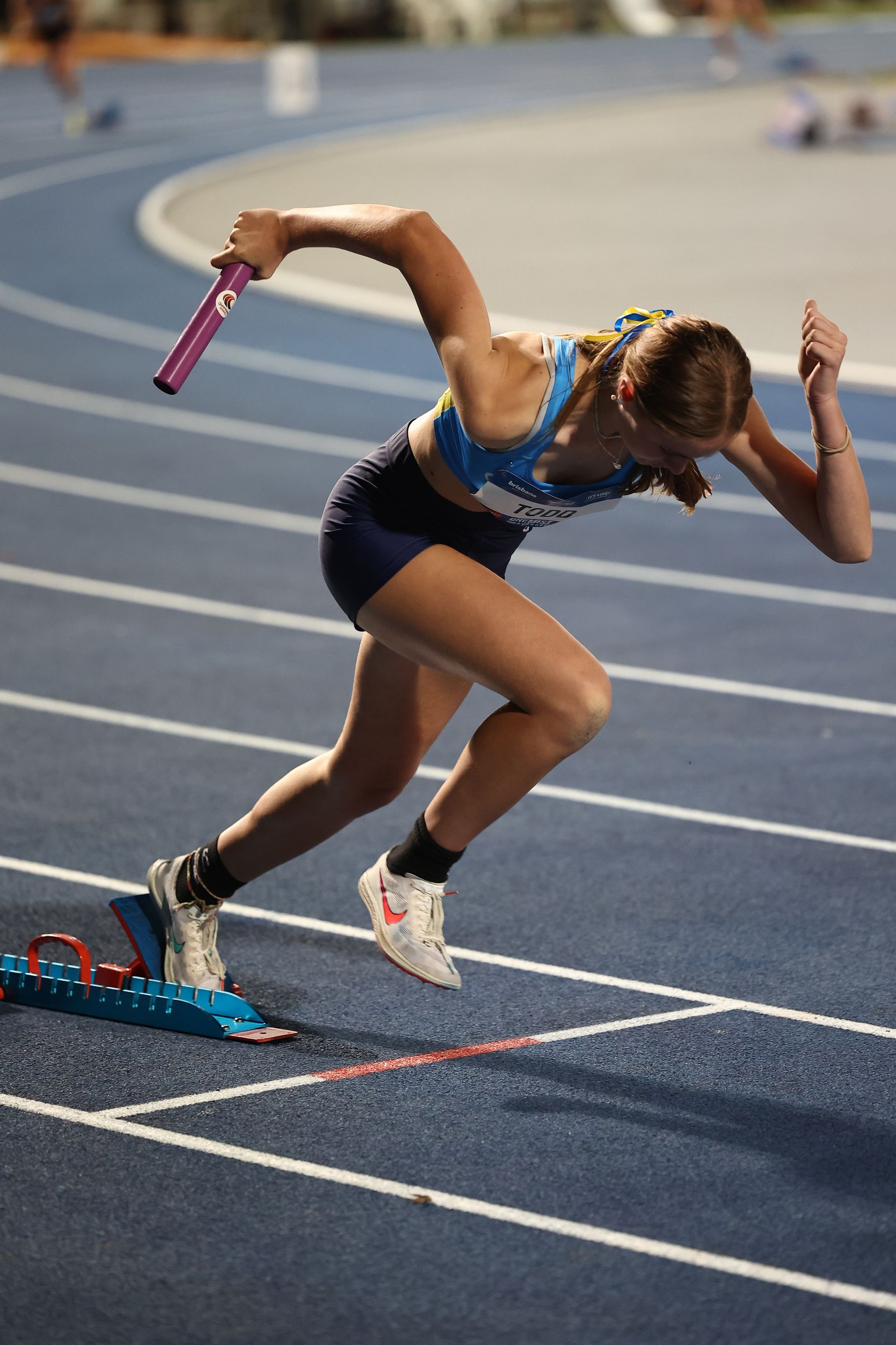 A woman is running on a track with a baton in her hand