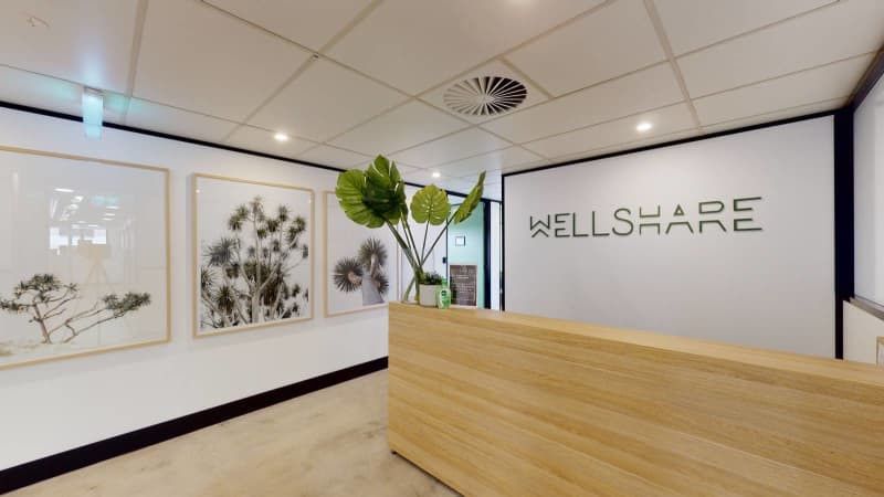 A wellshare office with a wooden desk and paintings on the wall.