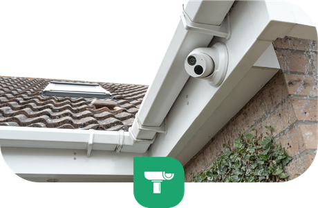Security camera mounted on a white fascia board, overlooking a roof with brown tiles.