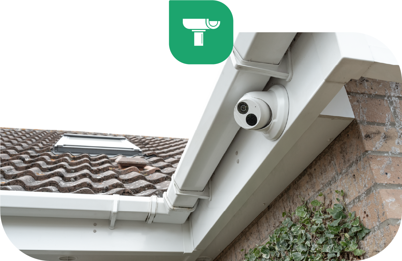 White security camera mounted on a white fascia and gutter. Brick wall and tiled roof in background.