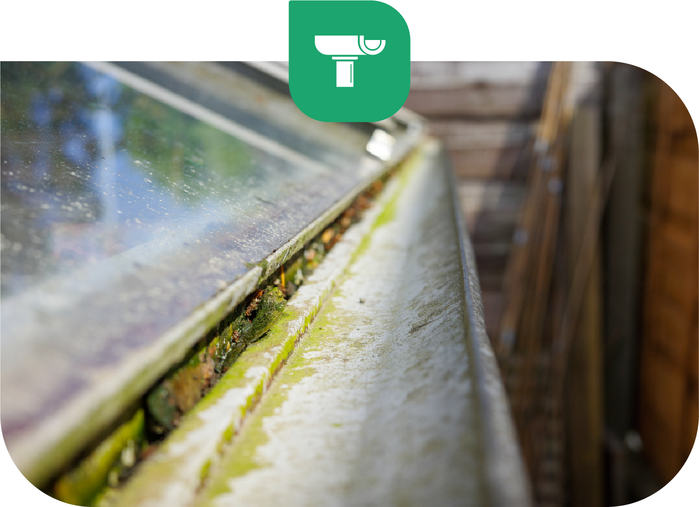 Close-up view of a dirty gutter with moss and debris. A green icon of a gutter cleaner is in the top corner.