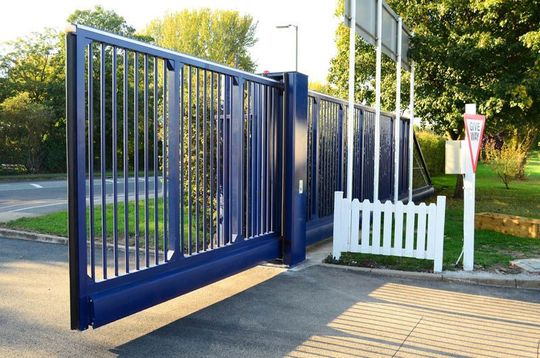A blue sliding gate with a white fence in front of it