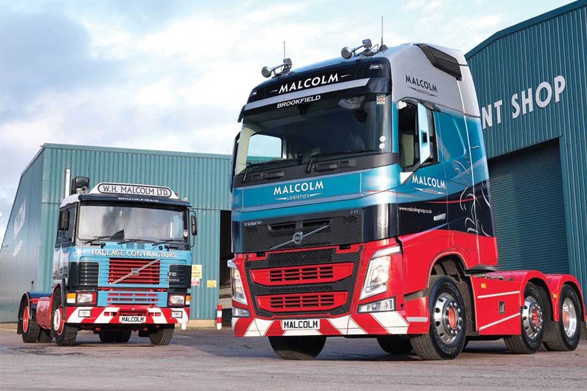 Two trucks are parked in front of a building that says ' nt shop ' on it