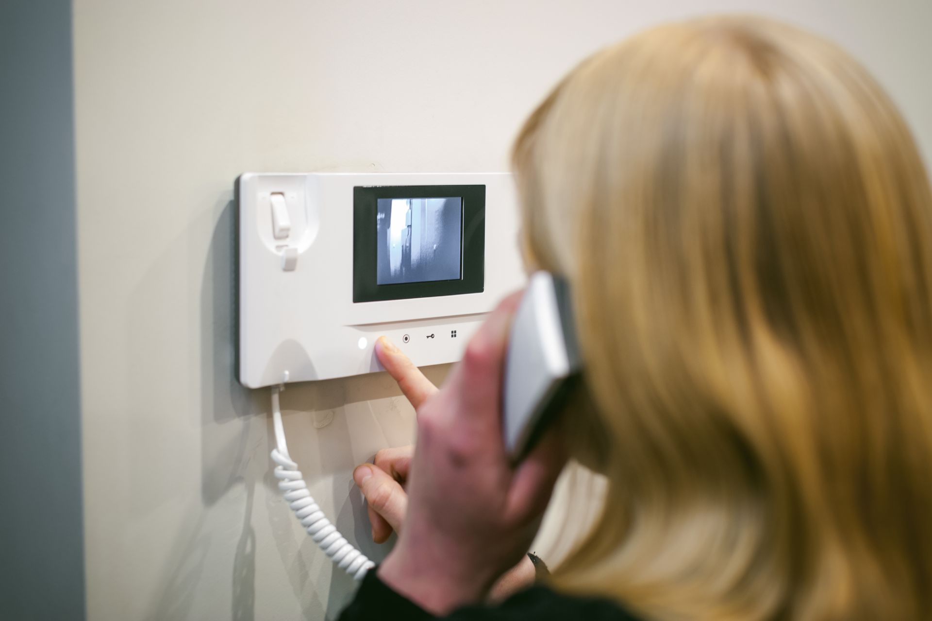 A woman is talking on a cell phone in front of a video doorbell.