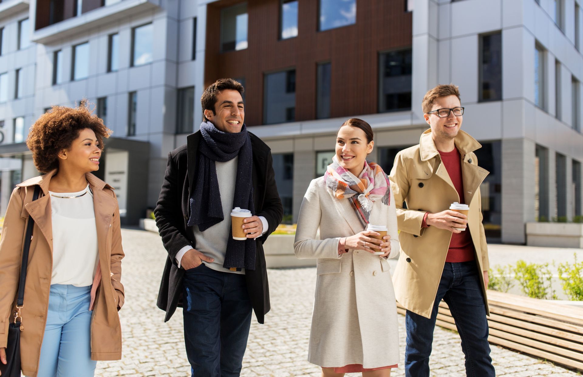 A group of people are walking down a sidewalk in front of a building.