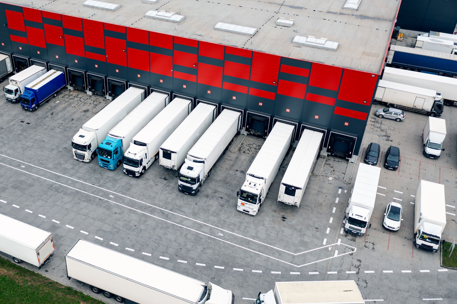 A bunch of trucks are parked in front of a warehouse.