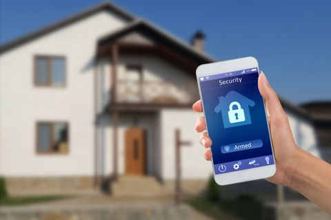 A person is holding a smart phone in front of a house.