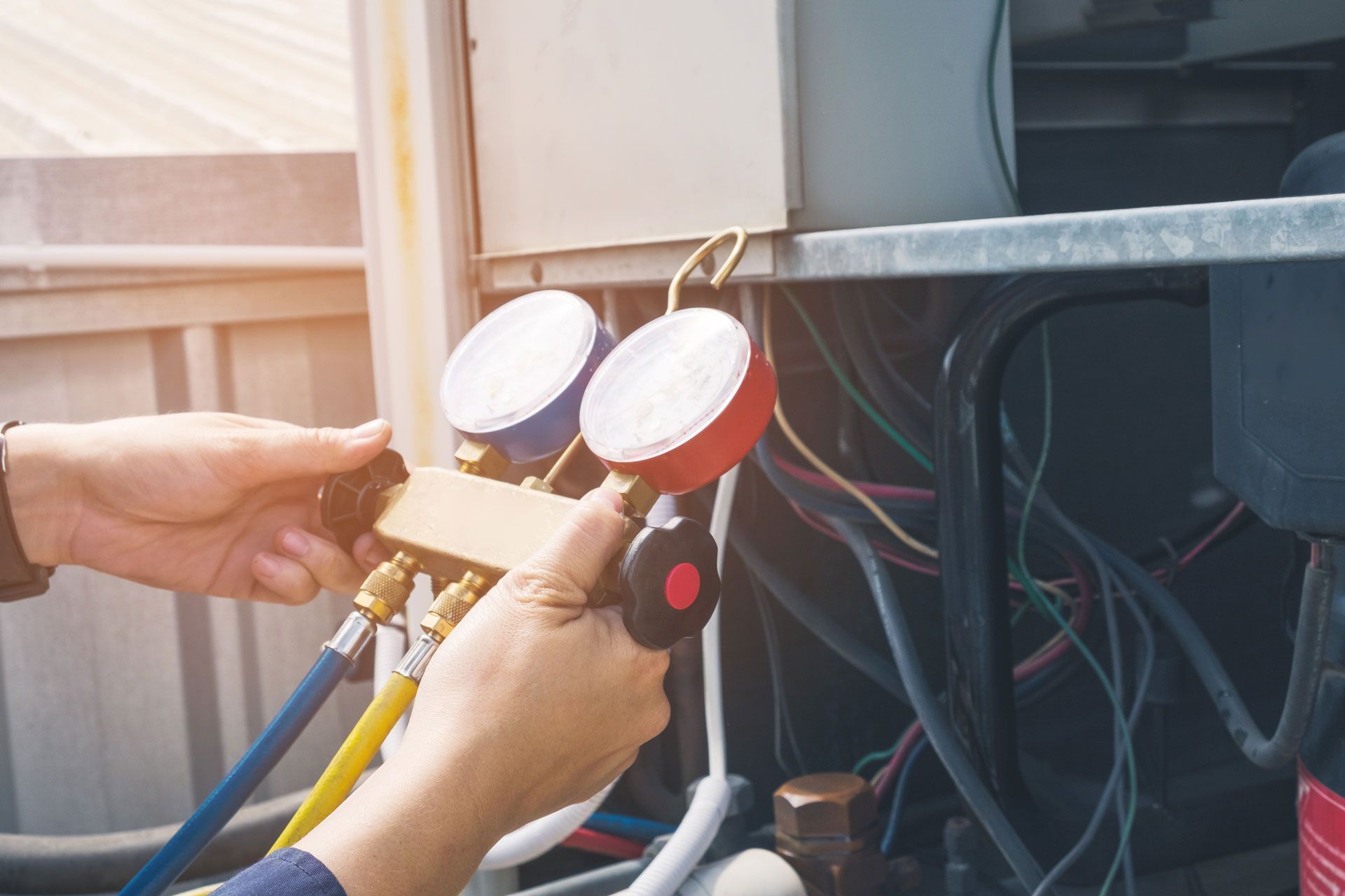 Technician checking HVAC gauges and hoses on an outdoor air conditioning unit