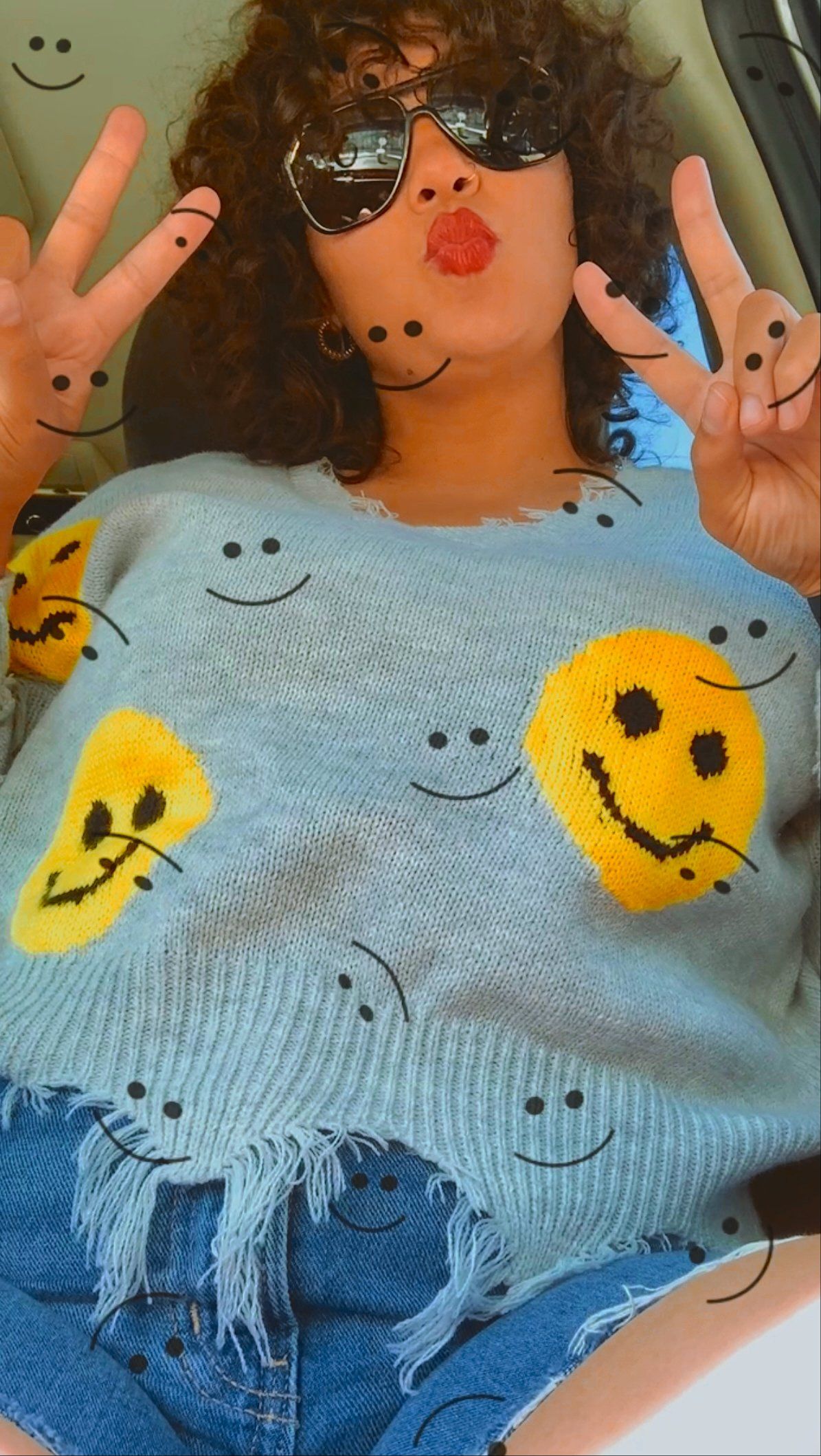 A woman wearing a sweater with smiley faces on it