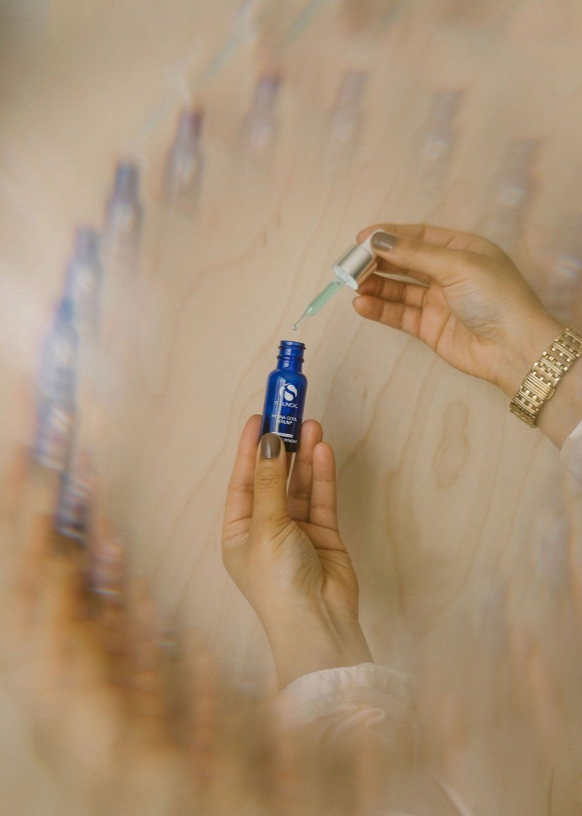 A person is holding a blue bottle with a dropper in their hand.