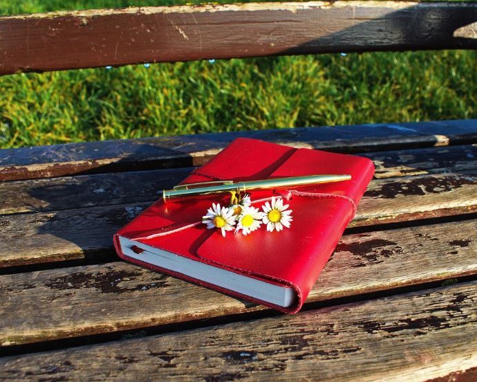 Red planner on rustic bench with daisies and pen, pre-planning brings comfort, funeral homes Oklahom