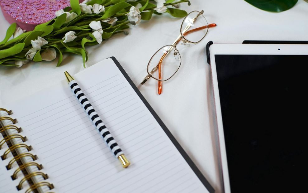 Fresh white flowers beside a spiral notebook, pen, and glasses, Norman, OK planning funeral wishes